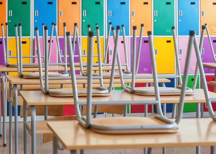 Modern empty classroom with colorful lockers and raised chairs on the tables