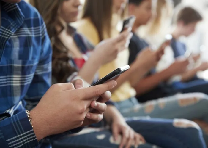 Close Up Of A Line Of High School Students Using Mobile Phones