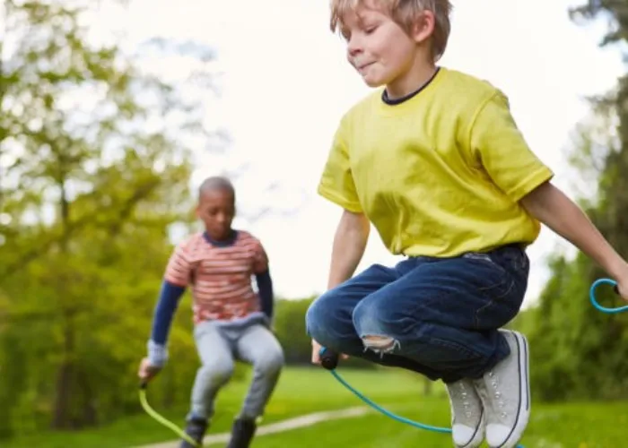 Junge im Park zusammen mit Freunden beim Wettbewerb im Seilspringen im Sommer