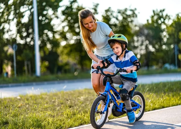 Young mother teaching son to ride a bike on the street