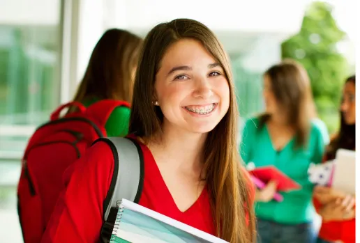 Girl smiling at school carrying backpack and books