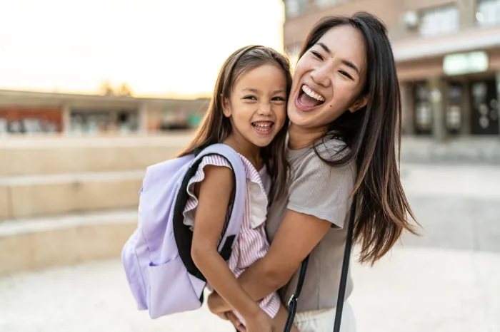 mom hugging her young girl after she goes back to school.