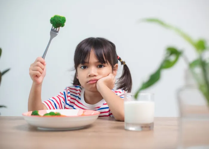 Nutrition & healthy eating habits for kids concept. Children do not like to eat vegetables. Little cute girl refuses to eat healthy vegetables.
